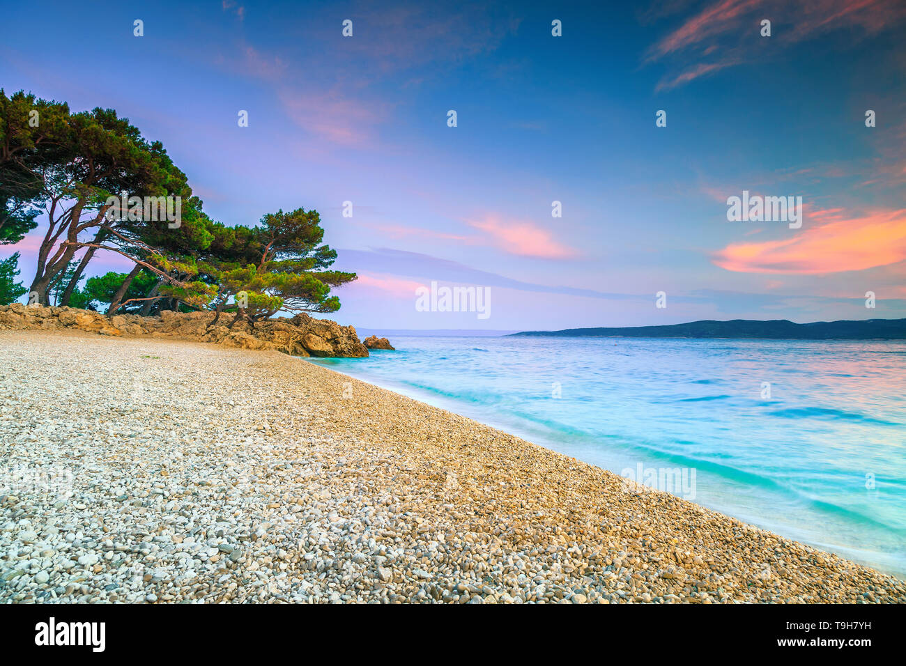 Beautiful mediterranean beach with pine trees and crystal clear water at sunset. Summer vacation place and gravel beach concept, Brela, Makarska rivie Stock Photo