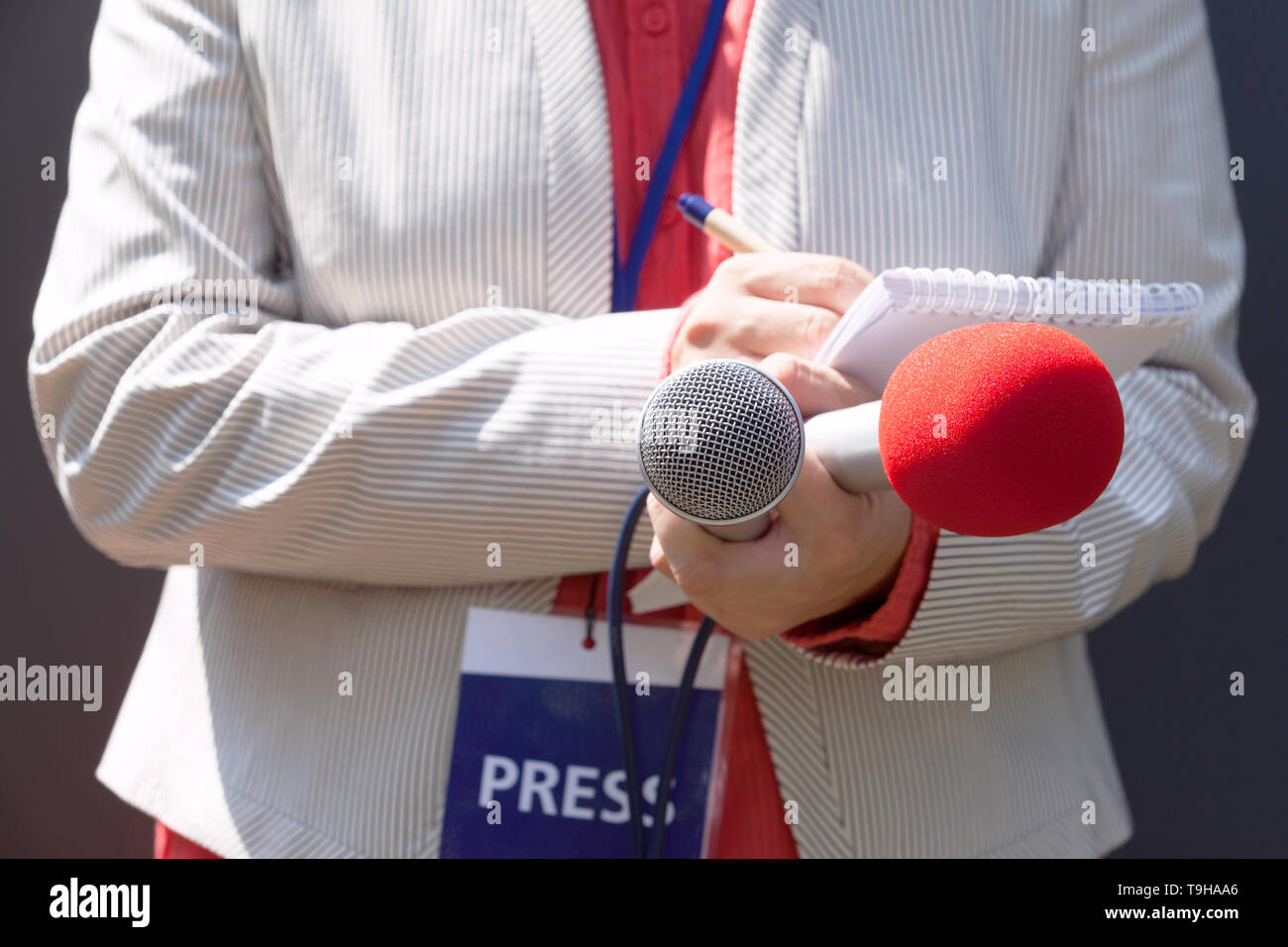 Female reporter at press conference, writing notes, holding microphone ...