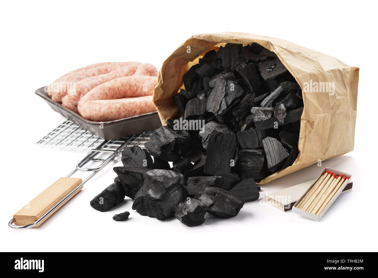 Set of tools and ingredients for barbecue. Paper bag of charcoal, grill, sausages and matches. Isolated. Stock Photo