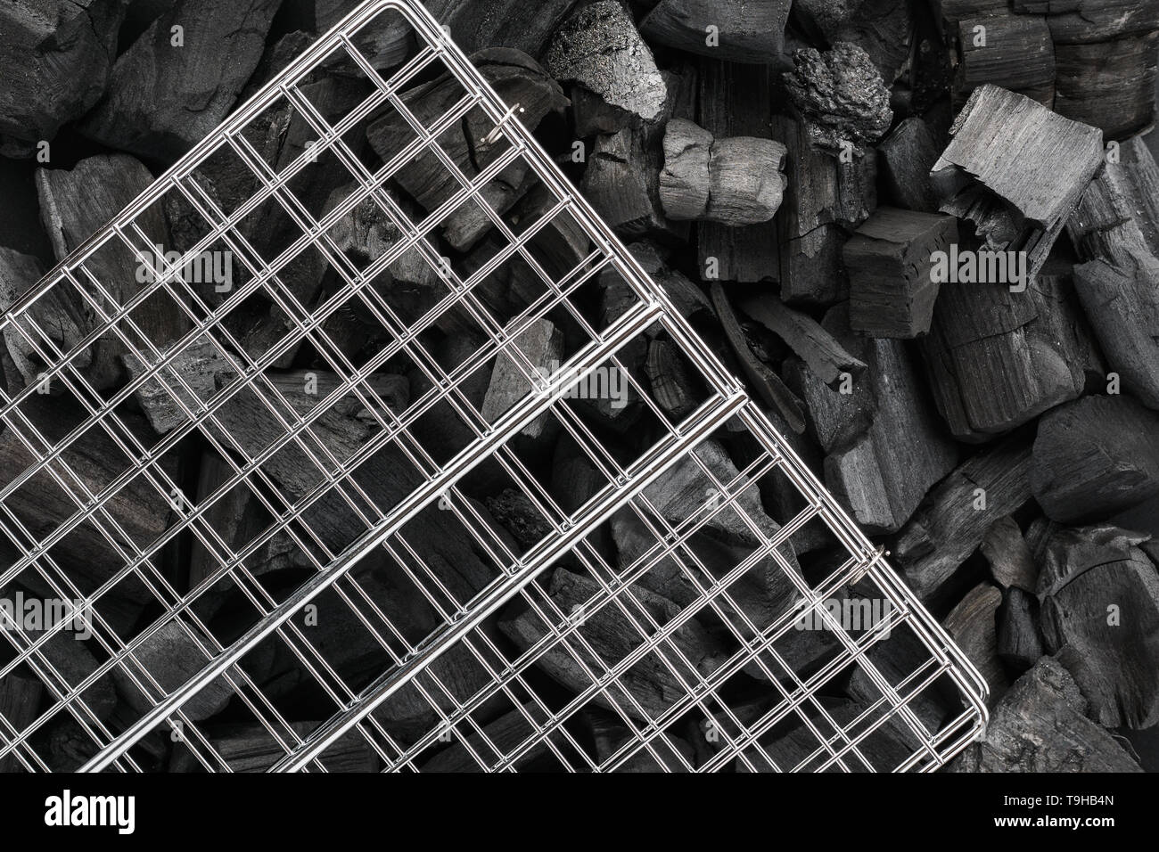 Barbecue grill grid on black charcoal pieces. BBQ preparation concept. Stock Photo