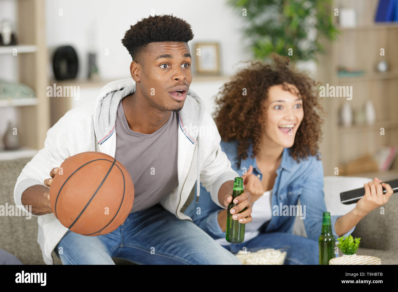 young couple watching basketball on tv Stock Photo Alamy