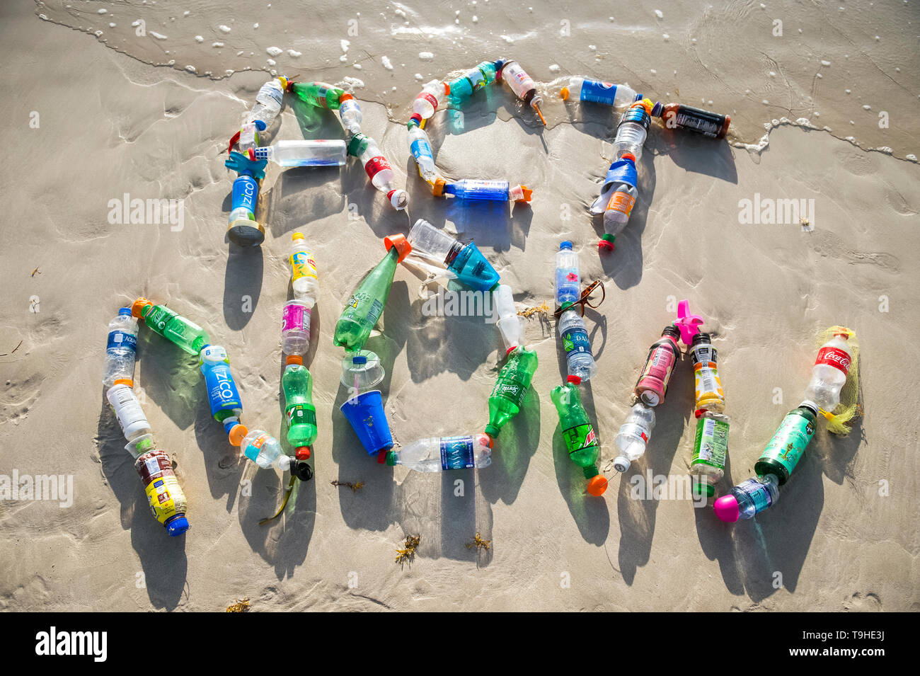 MIAMI - AUGUST, 2018: Ocean plastic pollution awareness message made from consumer drink and water bottles found on the beach spells out Act Now. Stock Photo