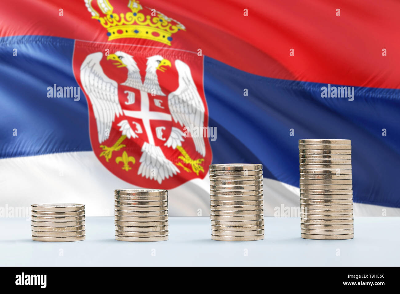 Serbia flag waving in the background with rows of coins for finance and business concept. Saving money. Stock Photo