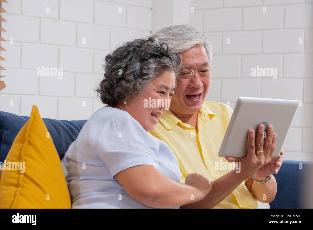Asian senior couple use tablet video call and talk to grandchild. Stock Photo