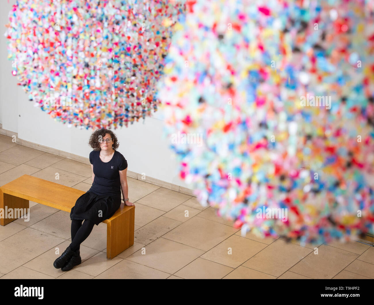 A visitor views 'As I Live and Breathe' - an installation composed of thousands of fragments of colourful waste polythene torn by hand from used shopping bags by artist Claire Morgan - at the Horniman Museum and Gardens, London, part of a series of specially commissioned works drawing on the theme of waste and the impact that humans have on their surroundings. Stock Photo