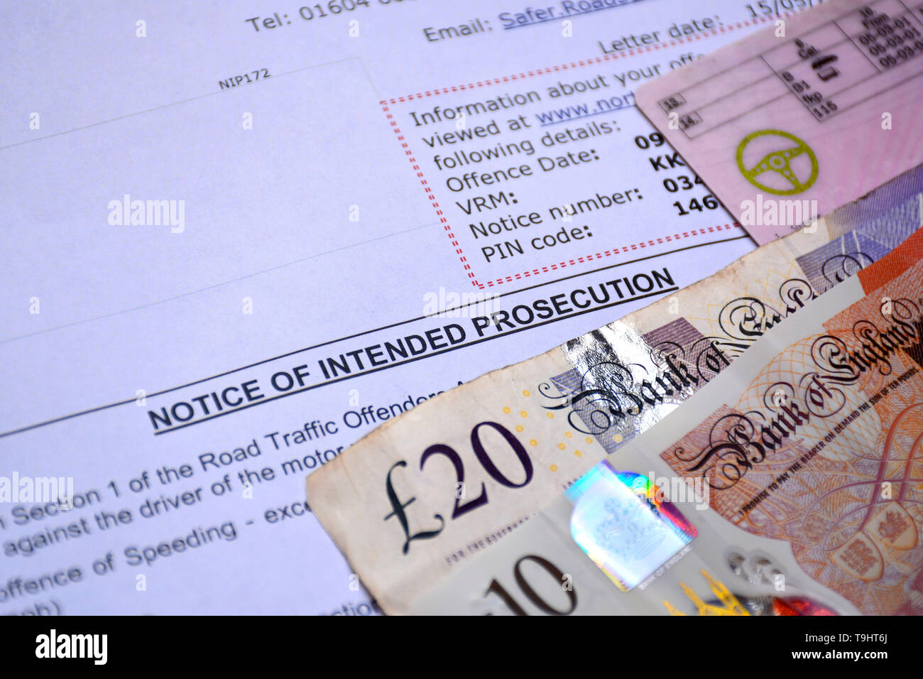 A Notice of Intended Prosecution (Speeding Fine) with driving license and bank notes on a table Stock Photo