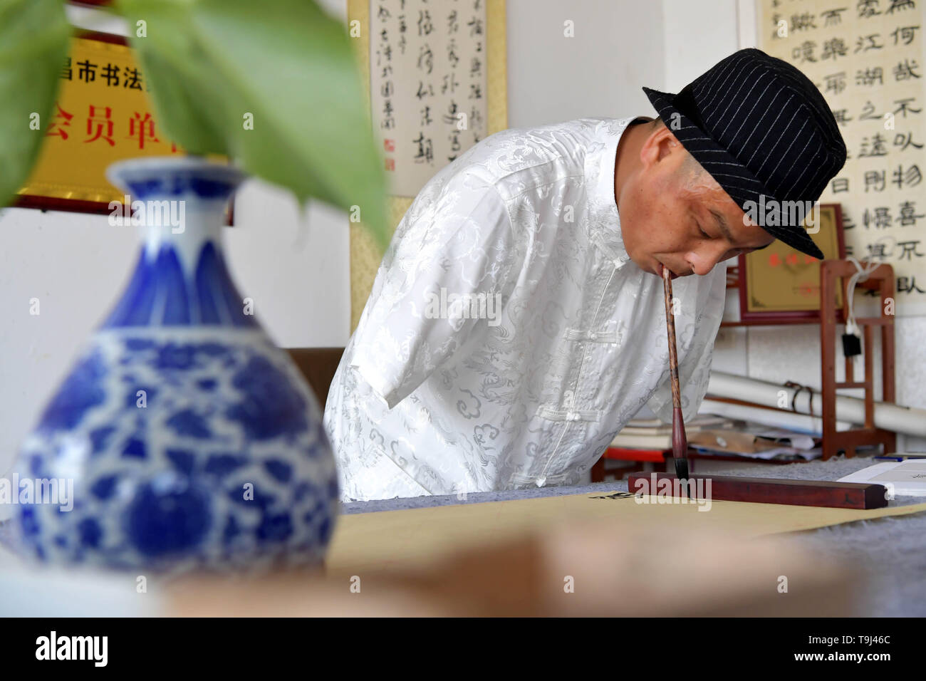 (190519) -- NANCHANG, May 19, 2019 (Xinhua) -- Cai Mujiang uses his mouth to write calligraphy at his studio in Xinjian District of Nanchang, capital of east China's Jiangxi Province, May 18, 2019. Thirty-five-year-old Cai Mujiang is a calligrapher with a difference. At the age of 23, Cai lost his arms in an accident. Despite the tragedy, Cai refused to give up and was able to take care of himself after arduous efforts.      In 2010, Cai began to learn to use his mouth to write Chinese calligraphy. After one year of learning, he mastered the skills and made a living through writing calligraphy Stock Photo