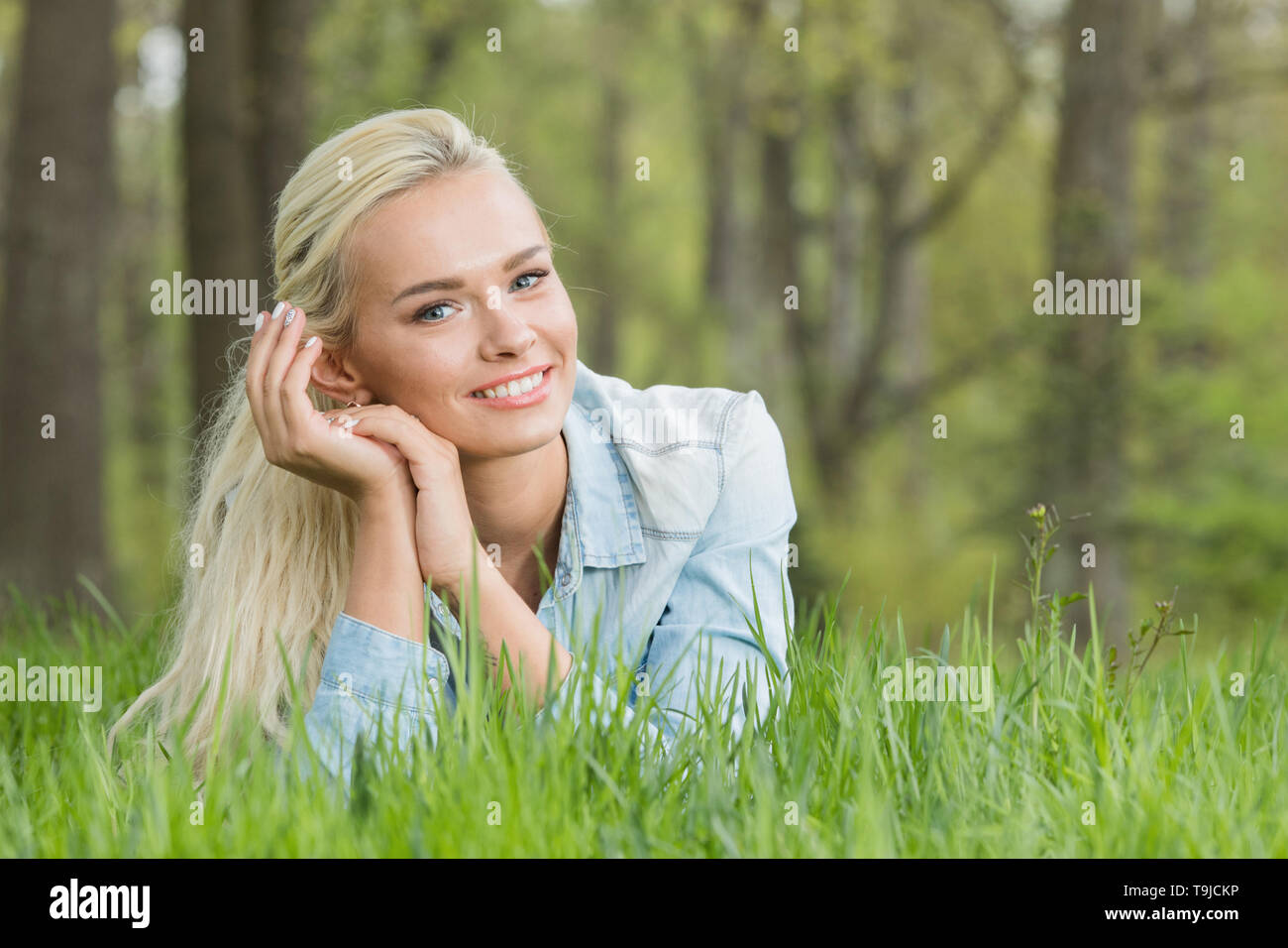 Blonde pretty girl laying on the grass in spring park and smiling Stock ...