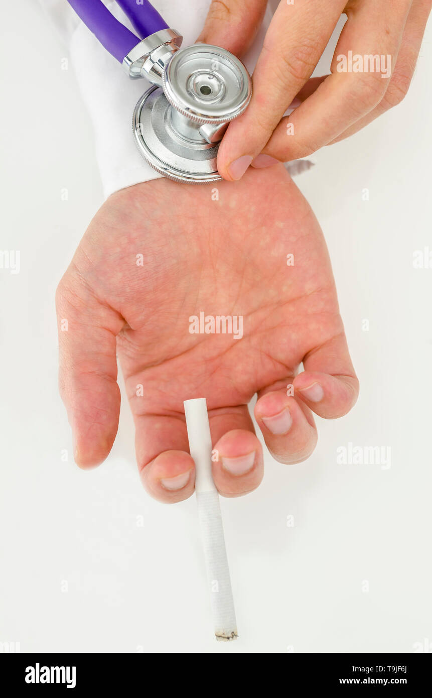 Holding stethoscope on smoking addict hand. Concept of smoking issue