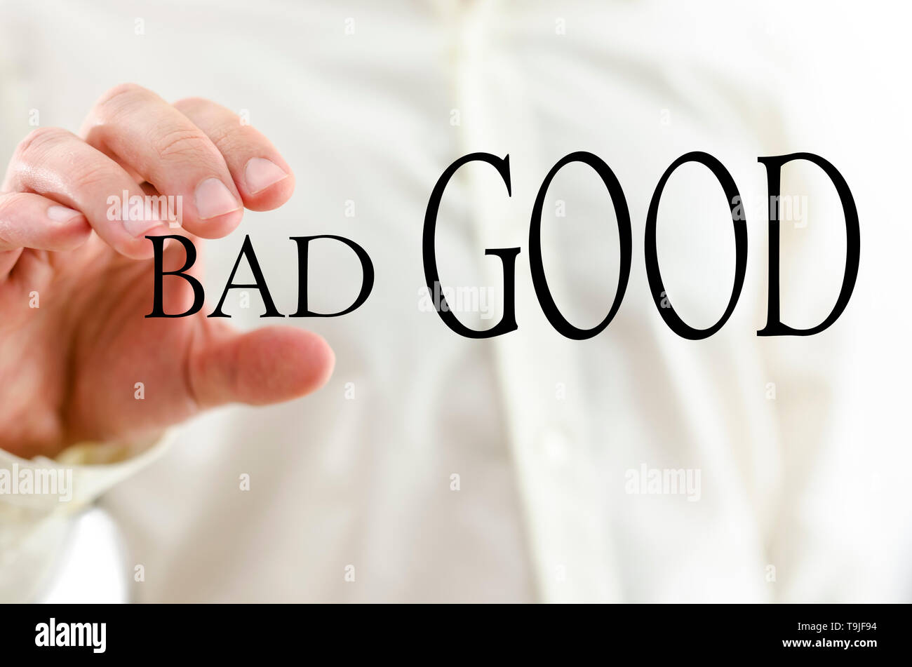 Male hand squeezing word Bad and letting word Good prevail. Stock Photo