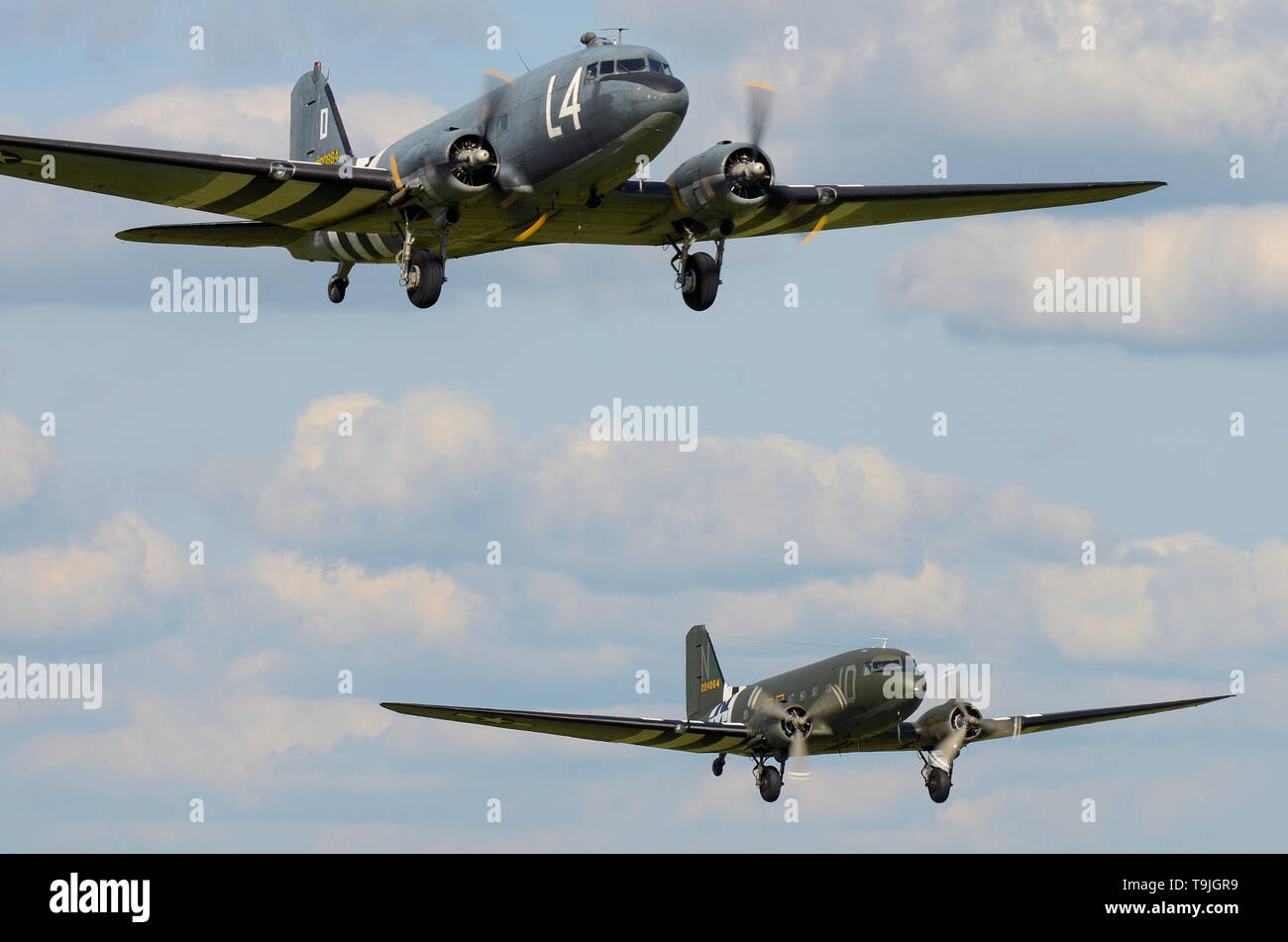 Second World war Douglas C-47 Skytrain planes in period camouflage markings - including D Day 'invasion stripes' - taking off together. World War Two Stock Photo
