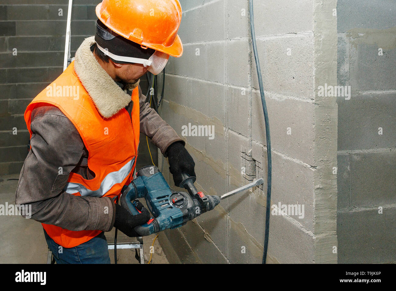 Slotting of the wall under the wiring with a perforator. Stock Photo