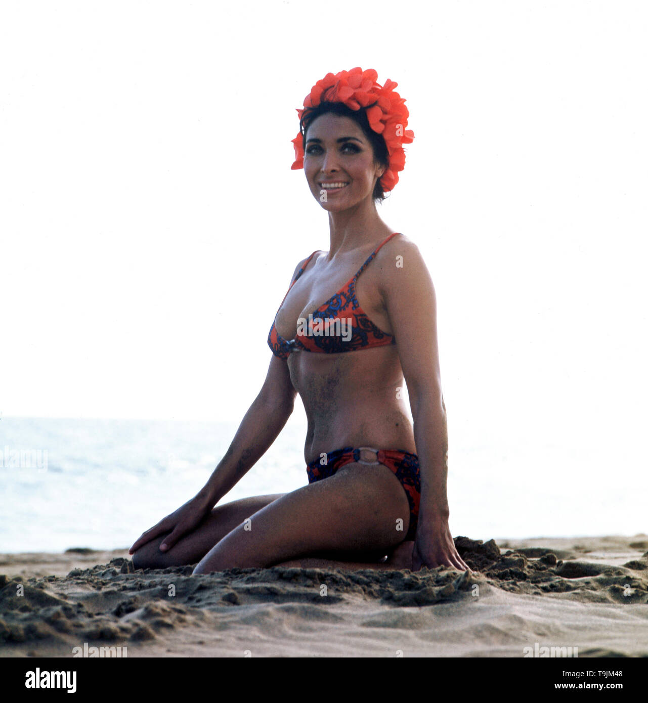 Die deutsche Schauspielerin und Sängerin Dunja Rajter im Urlaub posiert im  Bikini am Strand mit einer ausgefallenden Badehaube, ca. 1975. The German  actress and singer Dunja Rajter on vacation poses in a