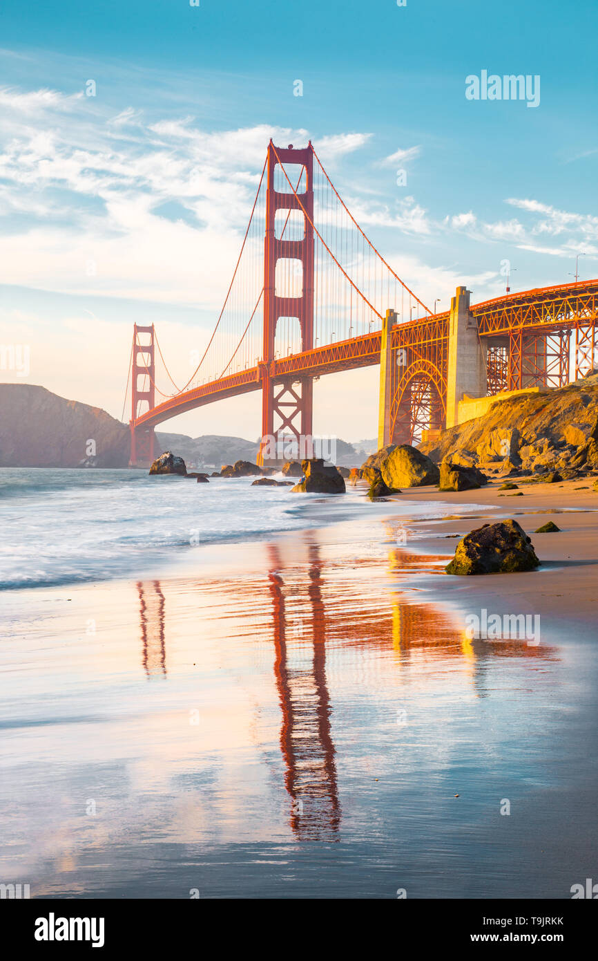 Classic panoramic view of famous Golden Gate Bridge seen from scenic Baker Beach in beautiful golden evening light on a sunny day with blue sky and cl Stock Photo