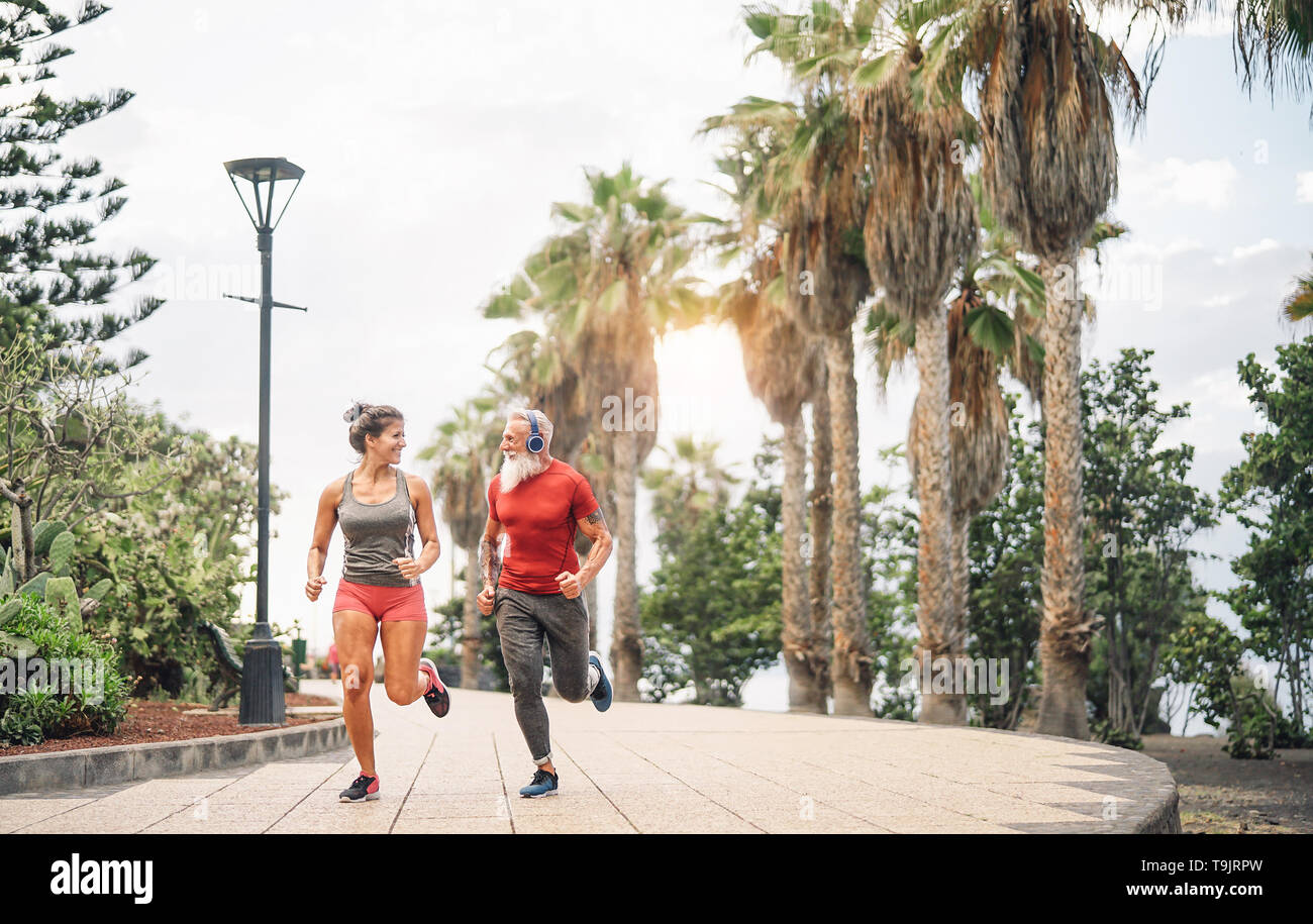 Happy fitness friends running at sunset outdoor - Couple of joggers training at evening time - People jogging, healthy,fit lifestyle and sport concept Stock Photo