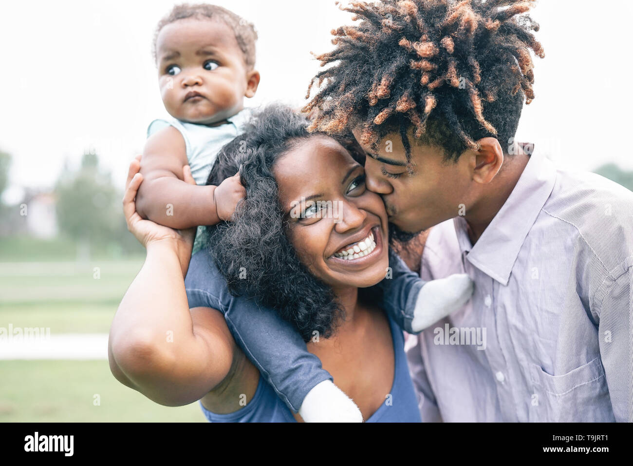 Happy black family having fun in a park outdoor - Mother and father with their daughter enjoying time together in a weekend day Stock Photo
