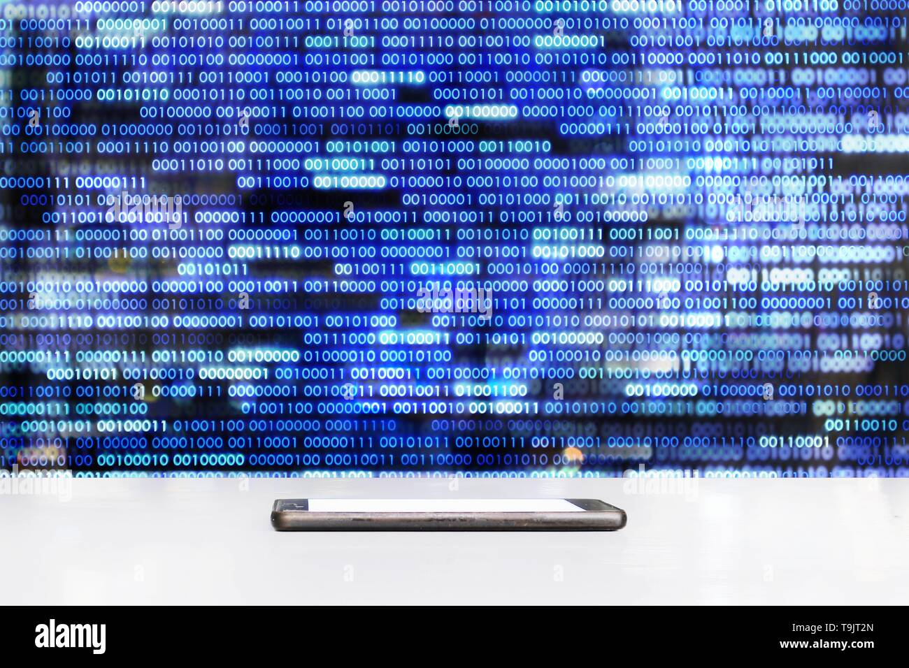 mobile phone sitting on glossy white table with  Blue binary data code background .empty screen mock up. conceptual data medium concepts. Stock Photo