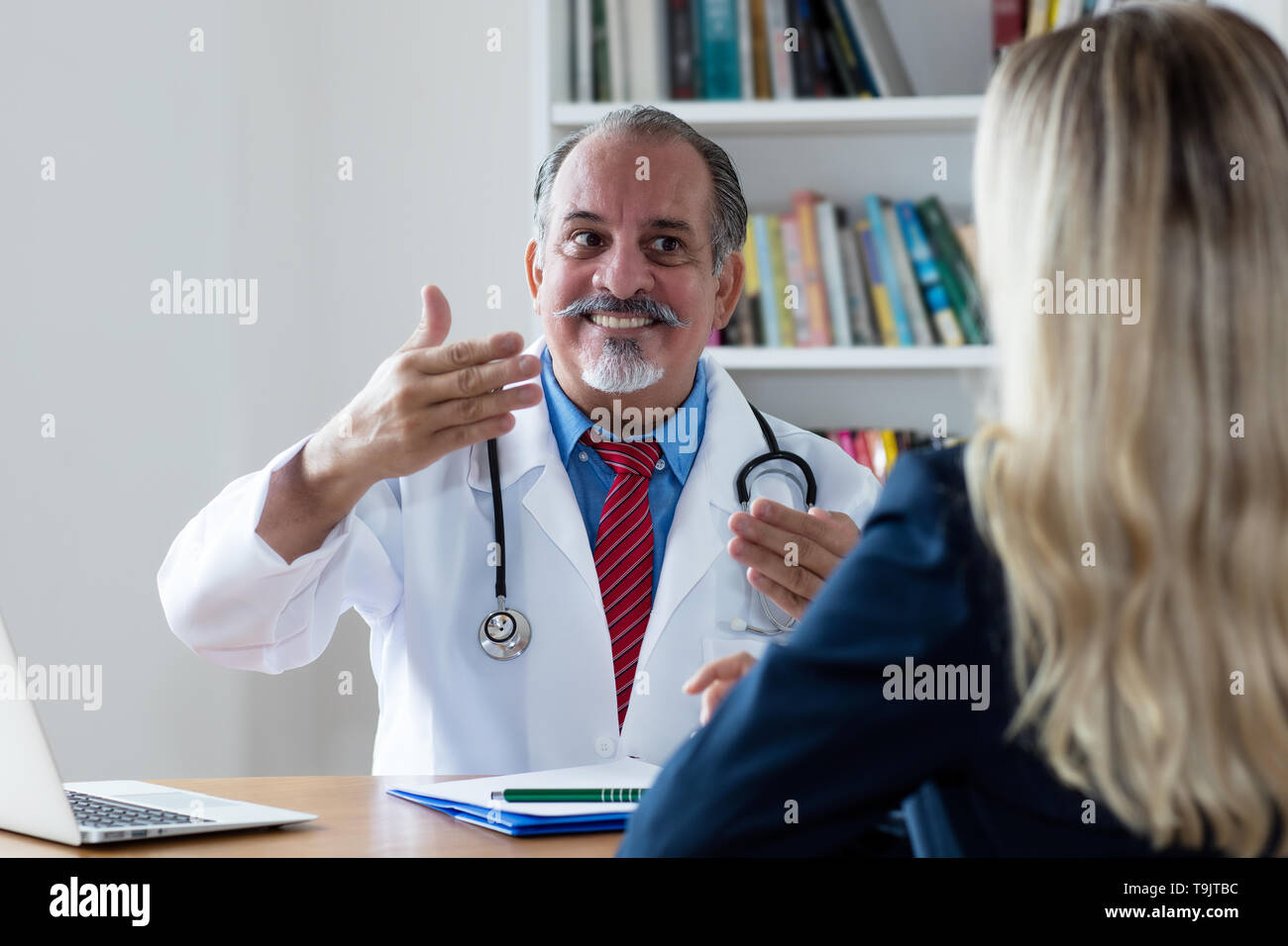 Laughing doctor explaining medical treatment to female patient at hospital Stock Photo