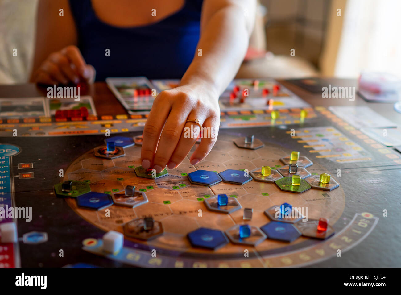 Balogunyom / Hungary -04.28.2019: Woman player placing pieces of the board game on the board while playing Terraforming Mars strategy game Stock Photo