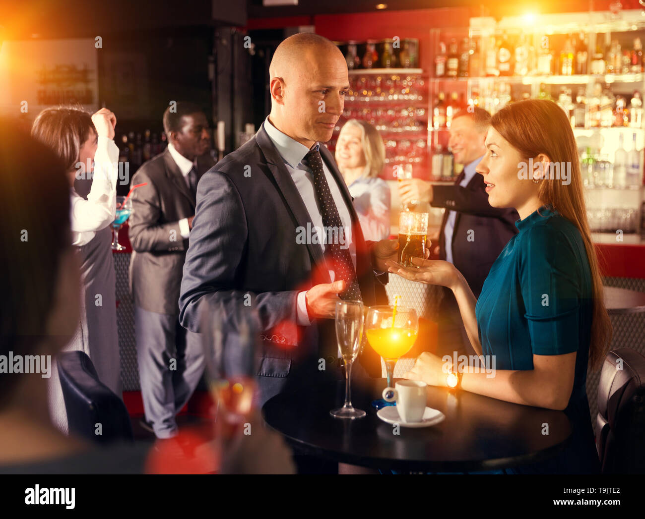 Smiling man and woman drinking alcohol and having conversation on ...
