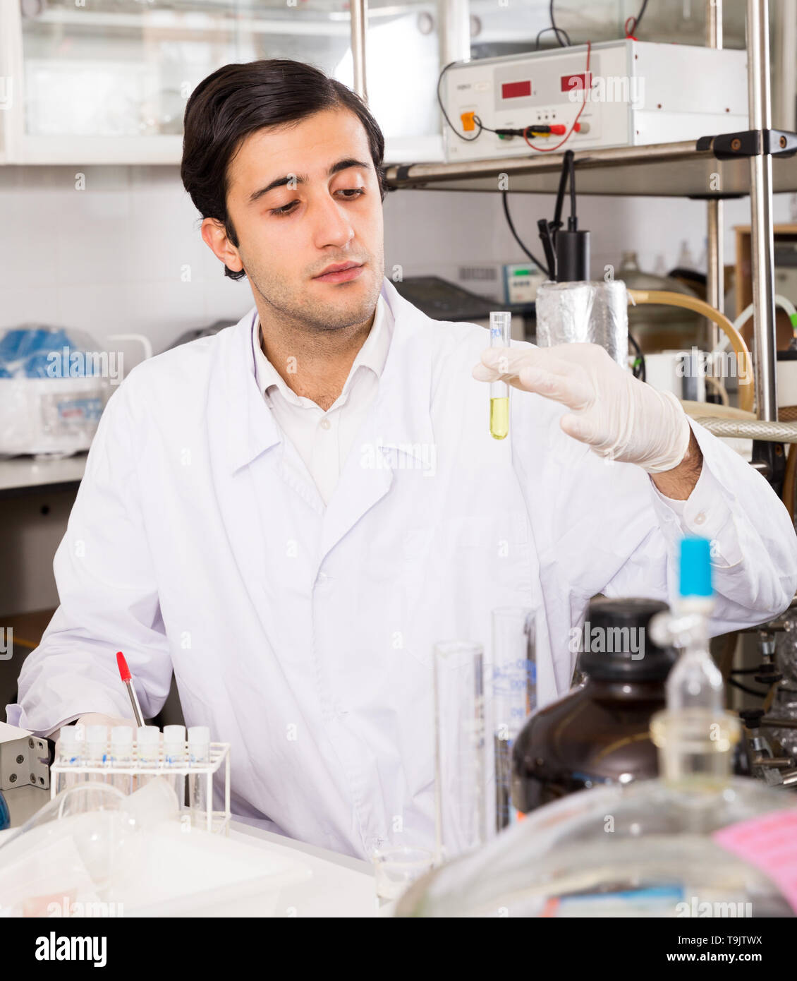 Portrait of young focused lab technician writing report on results of