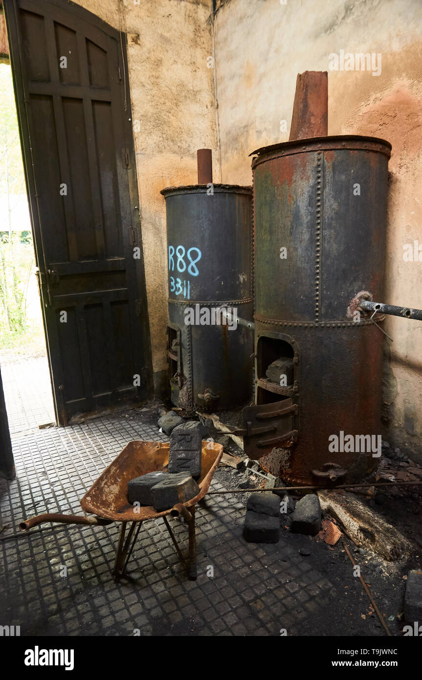 Interior of neglected facilities with rusty metal boilers and coal bricks at the Canfranc International railway station (Pyrenees,Huesca,Aragon,Spain) Stock Photo