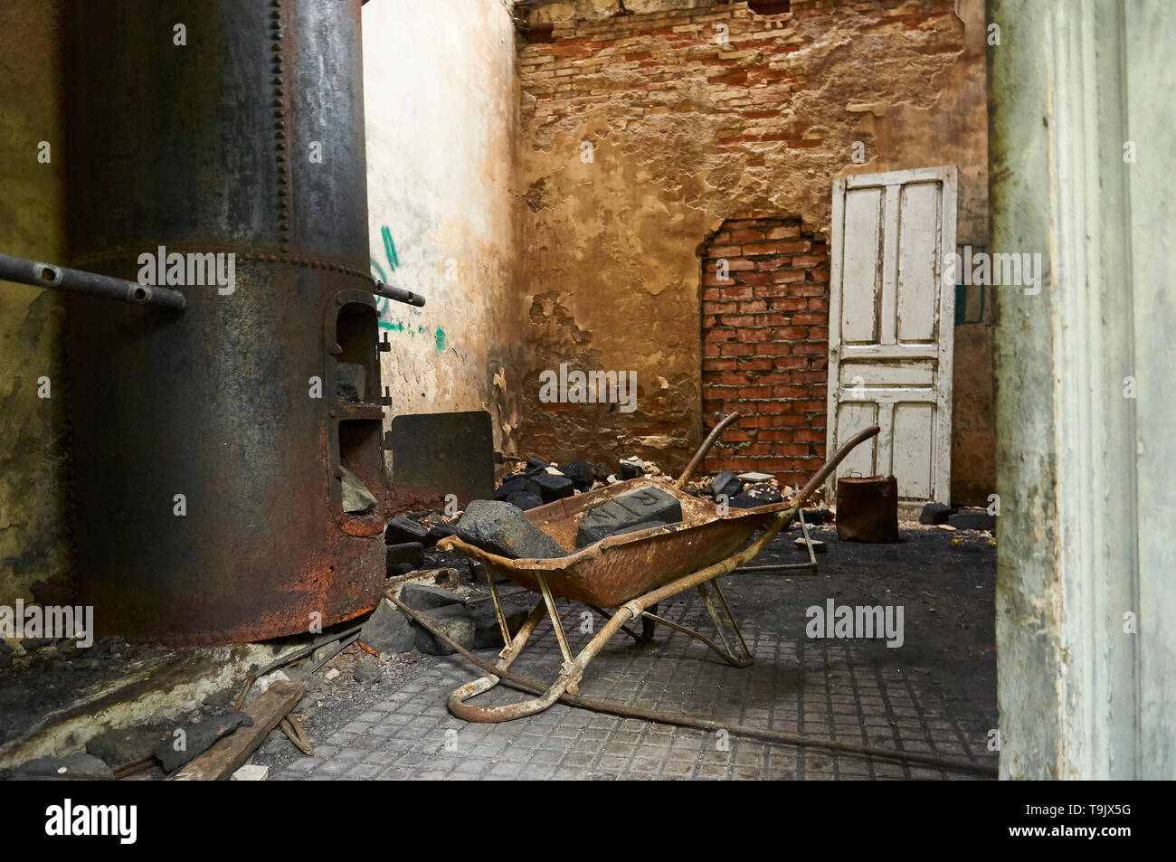Neglected facilities with rusty metal boiler and wheelbarrow with coal bricks at the Canfranc International railway station (Huesca,Aragon,Spain) Stock Photo