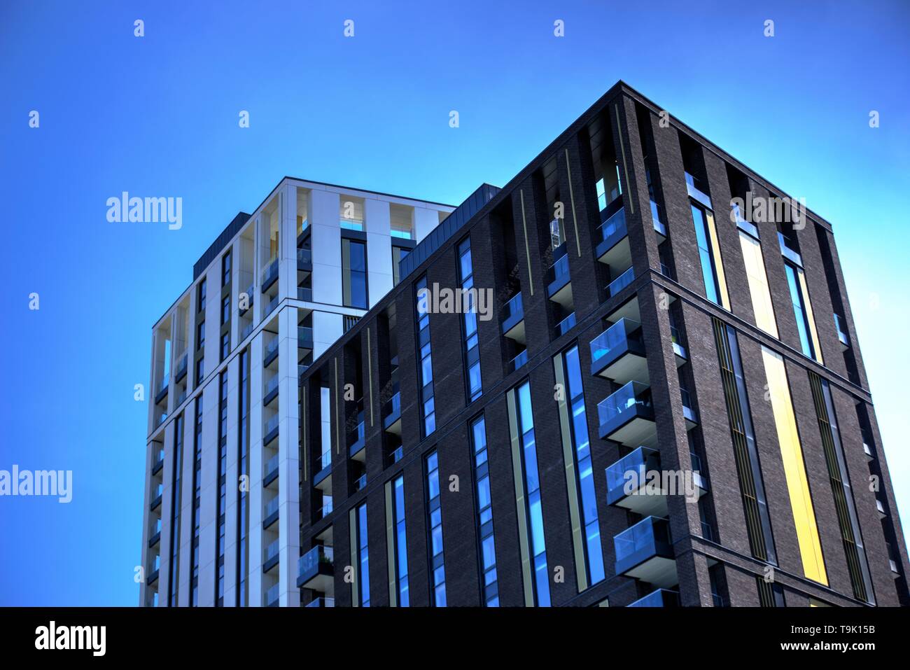Two modern building facades in white and brown against a blue sky Stock Photo