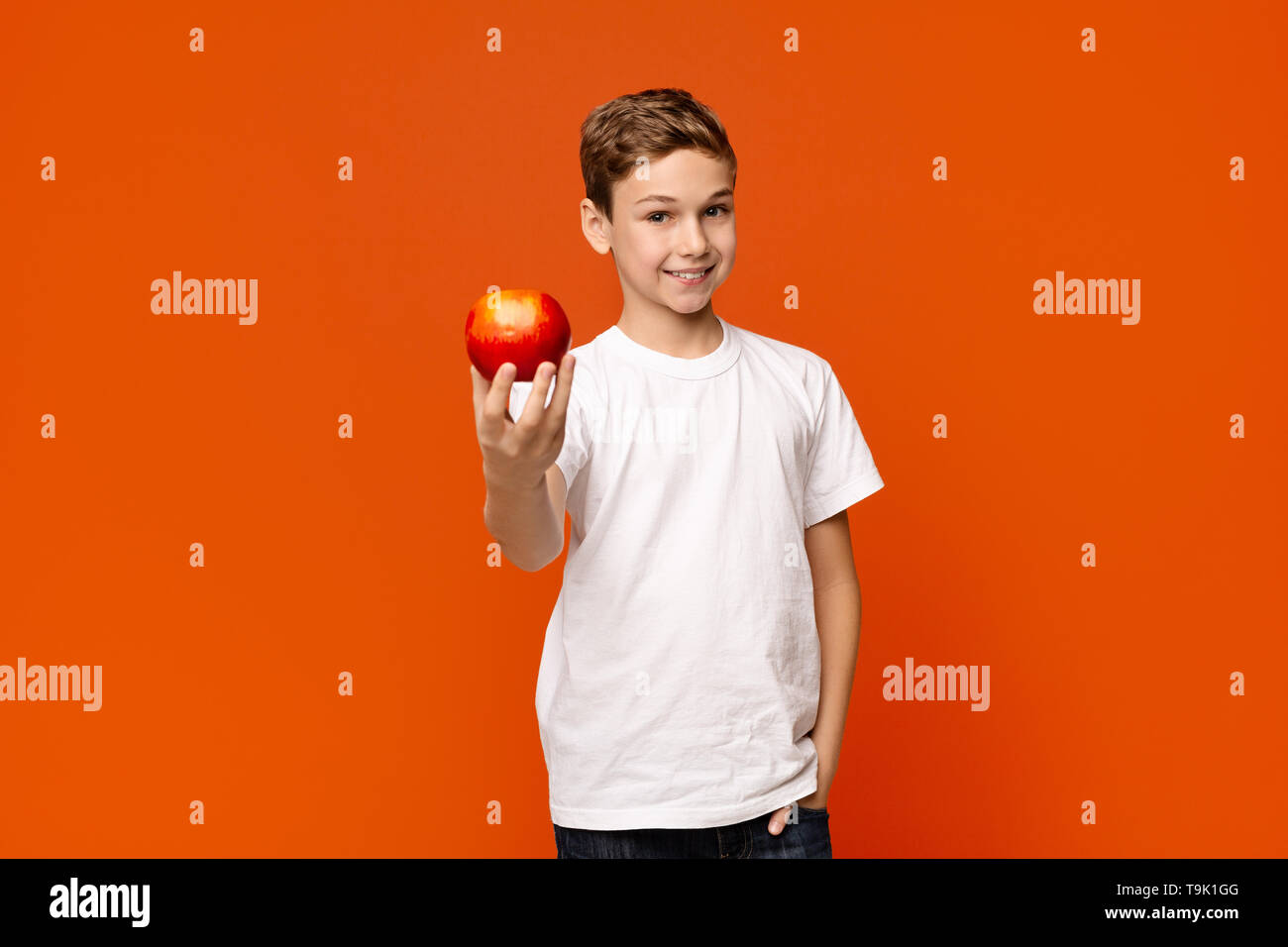 Positive little boy offering fresh red apple on camera Stock Photo - Alamy