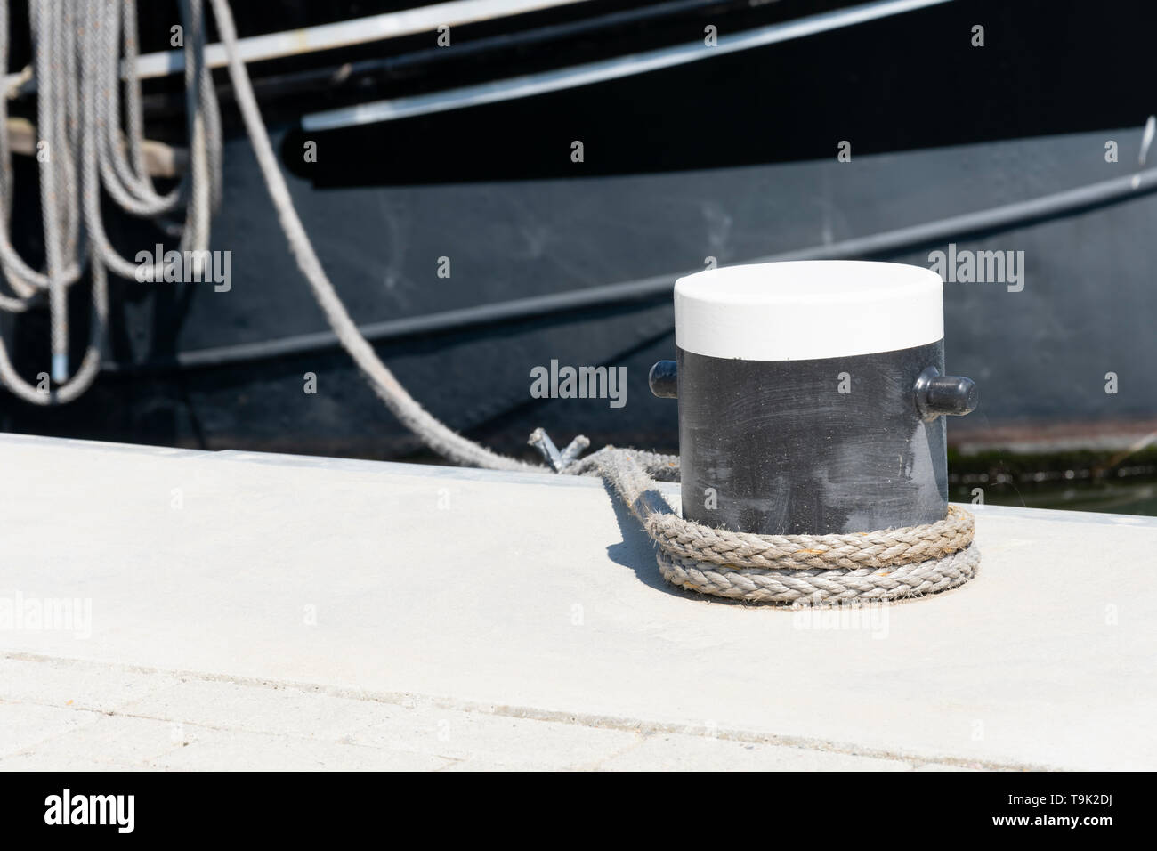 A black and white bollard with a rope around it Stock Photo