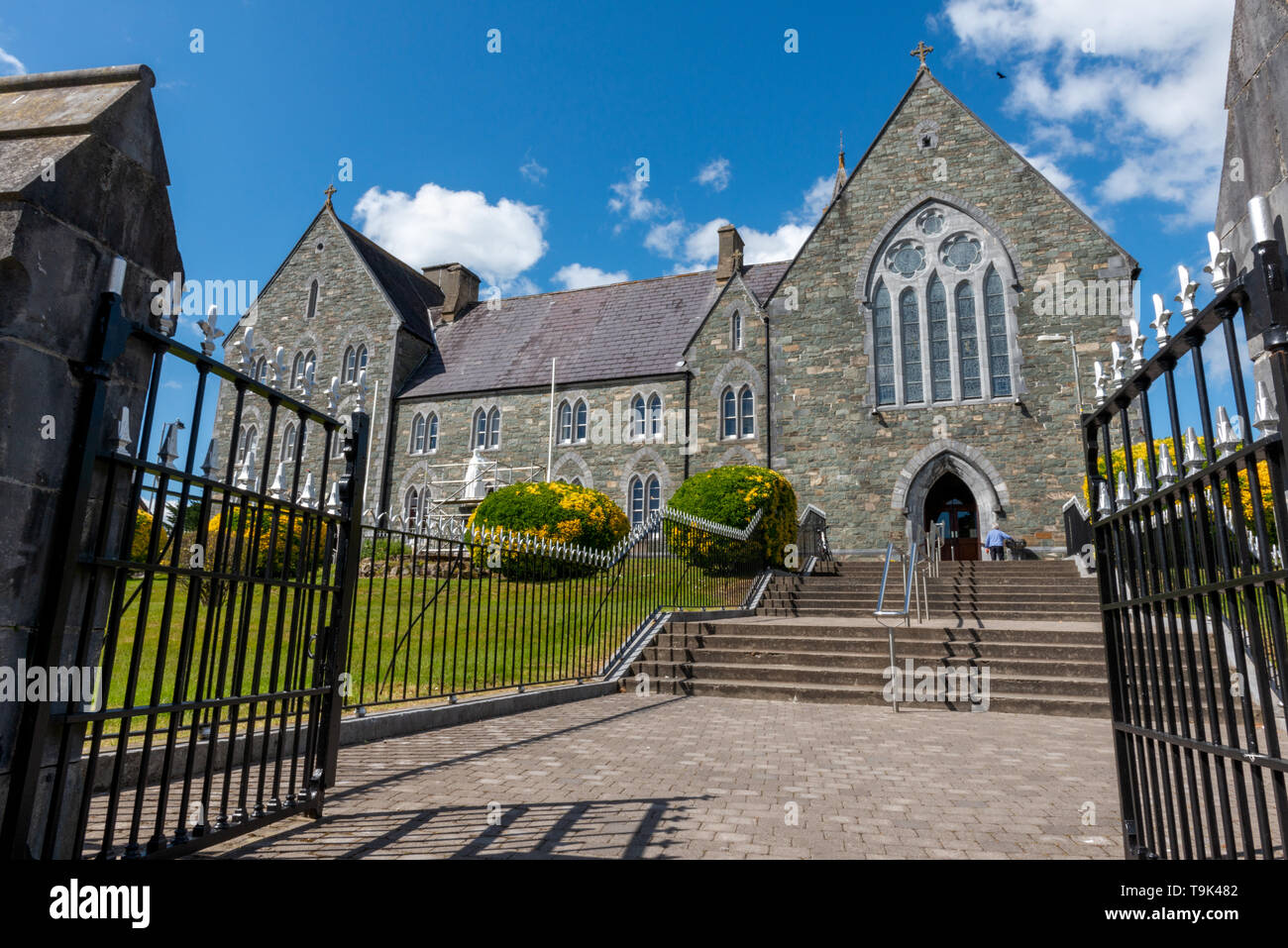 Religion church Ireland Gothic Revival style friary and lone senior man at The Franciscan Friary church in Killarney County Kerry Ireland. Stock Photo