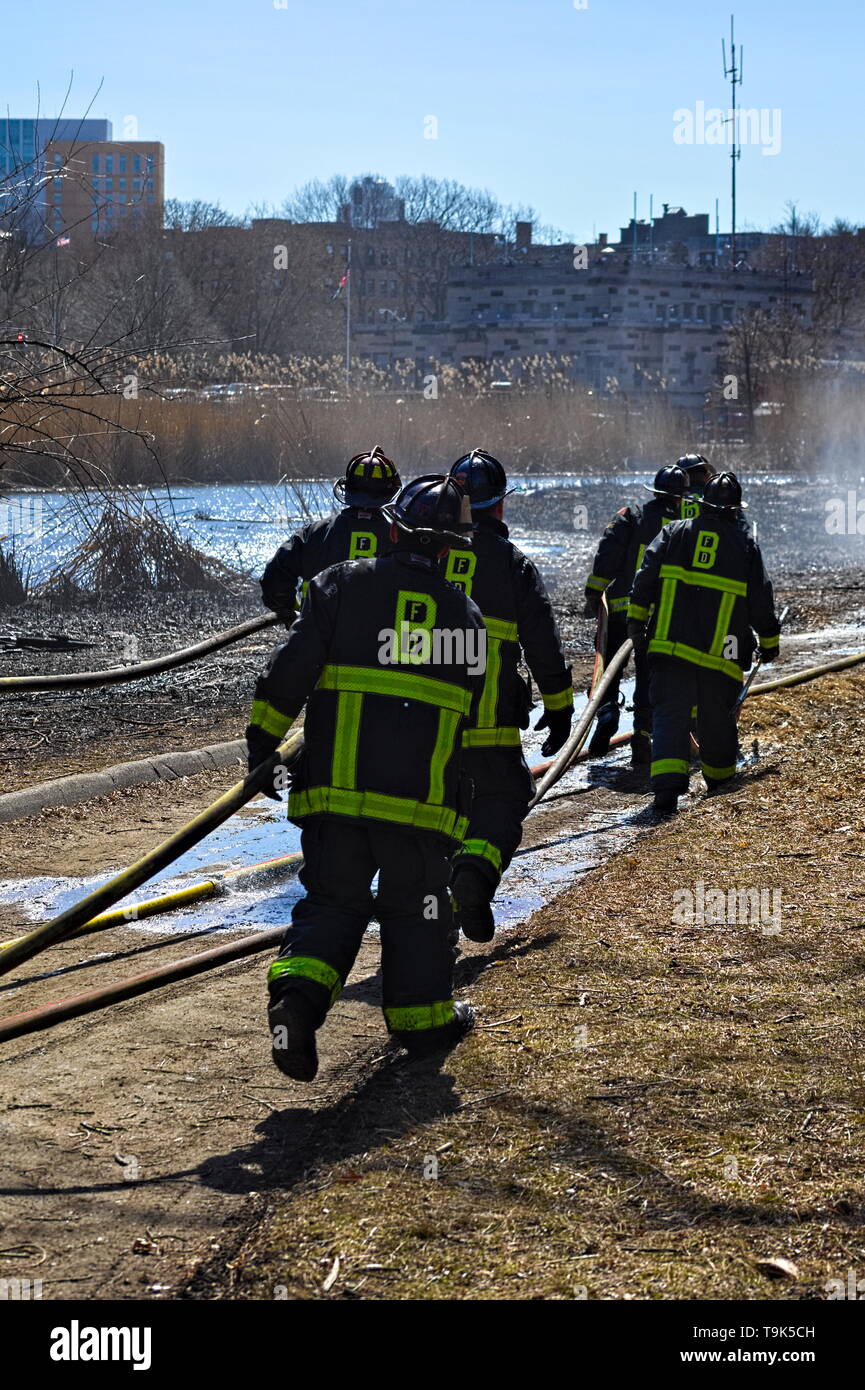 Boston Fire Department firefighters finish putting out a brush fire in the Fens on March 28, 2019. Stock Photo