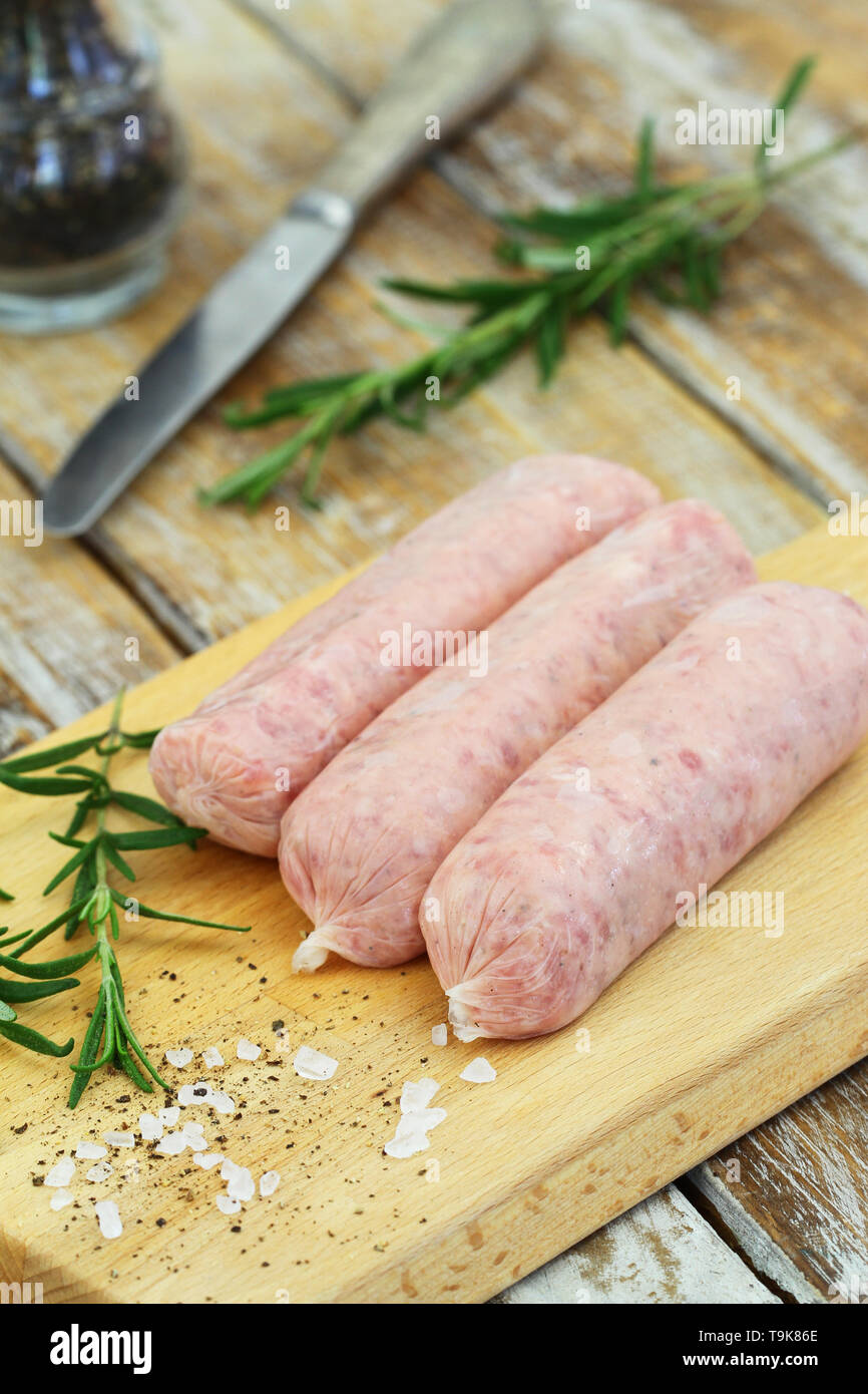 Prime raw British pork sausages on wooden board Stock Photo