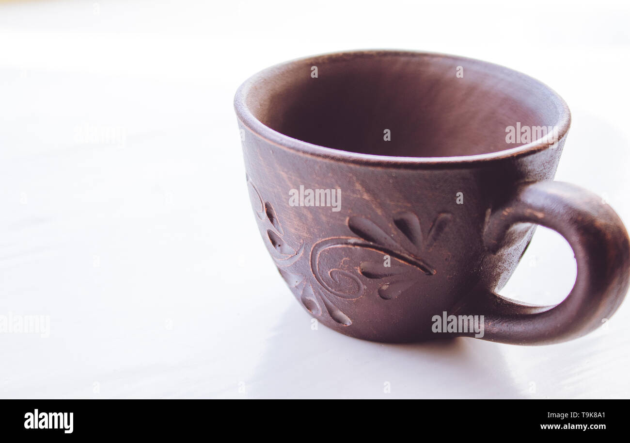 Clay cup stands on a white background. Close-up. Stock Photo