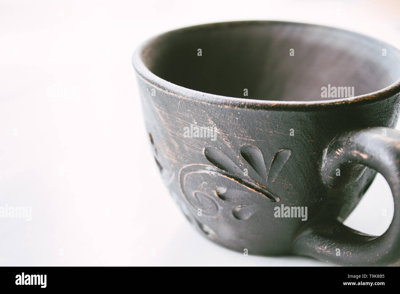 Clay cup stands on a white background. Close-up. Stock Photo