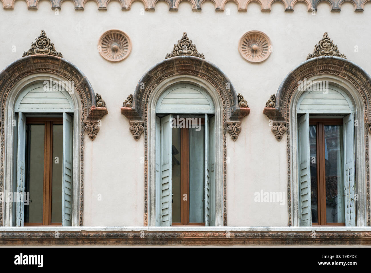 row of highly decorated Venetian windows on building wall Stock Photo