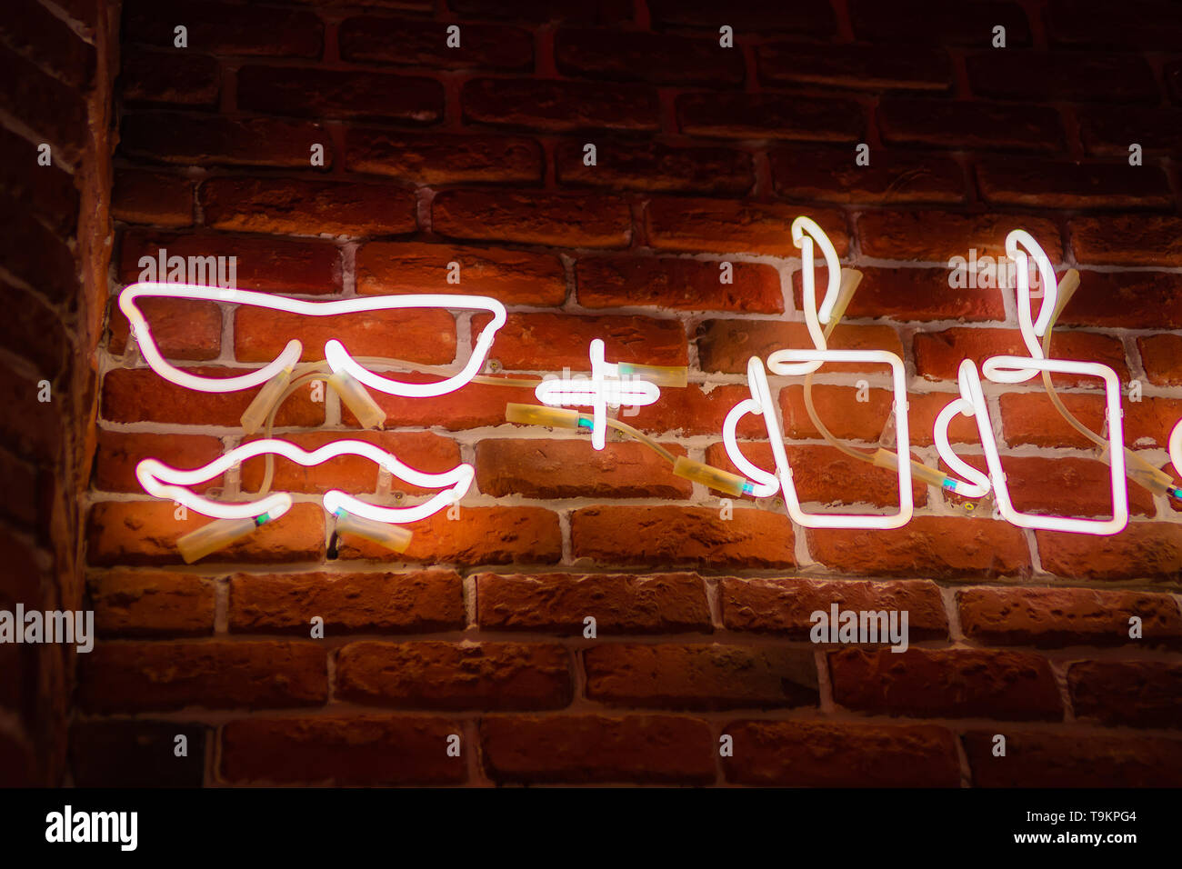 Neon sign with cups of coffee on the background of a red brick wall. Abstract hipster background. Stock Photo