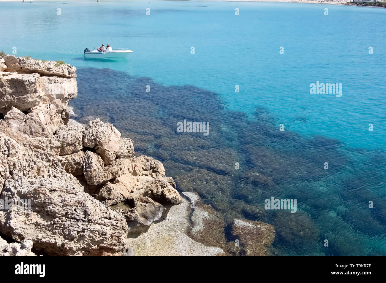 White boat and transparent blue sea near the rocky shore in the resort of Ayia Napa, Cyprus. Stock Photo