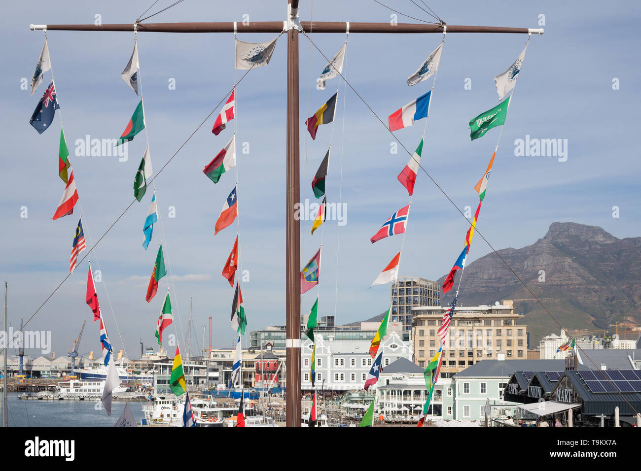 a large or huge masthead standing centrally in the V&A Waterfront in Cape Town with many or numerous international countries flags flying in the wind Stock Photo