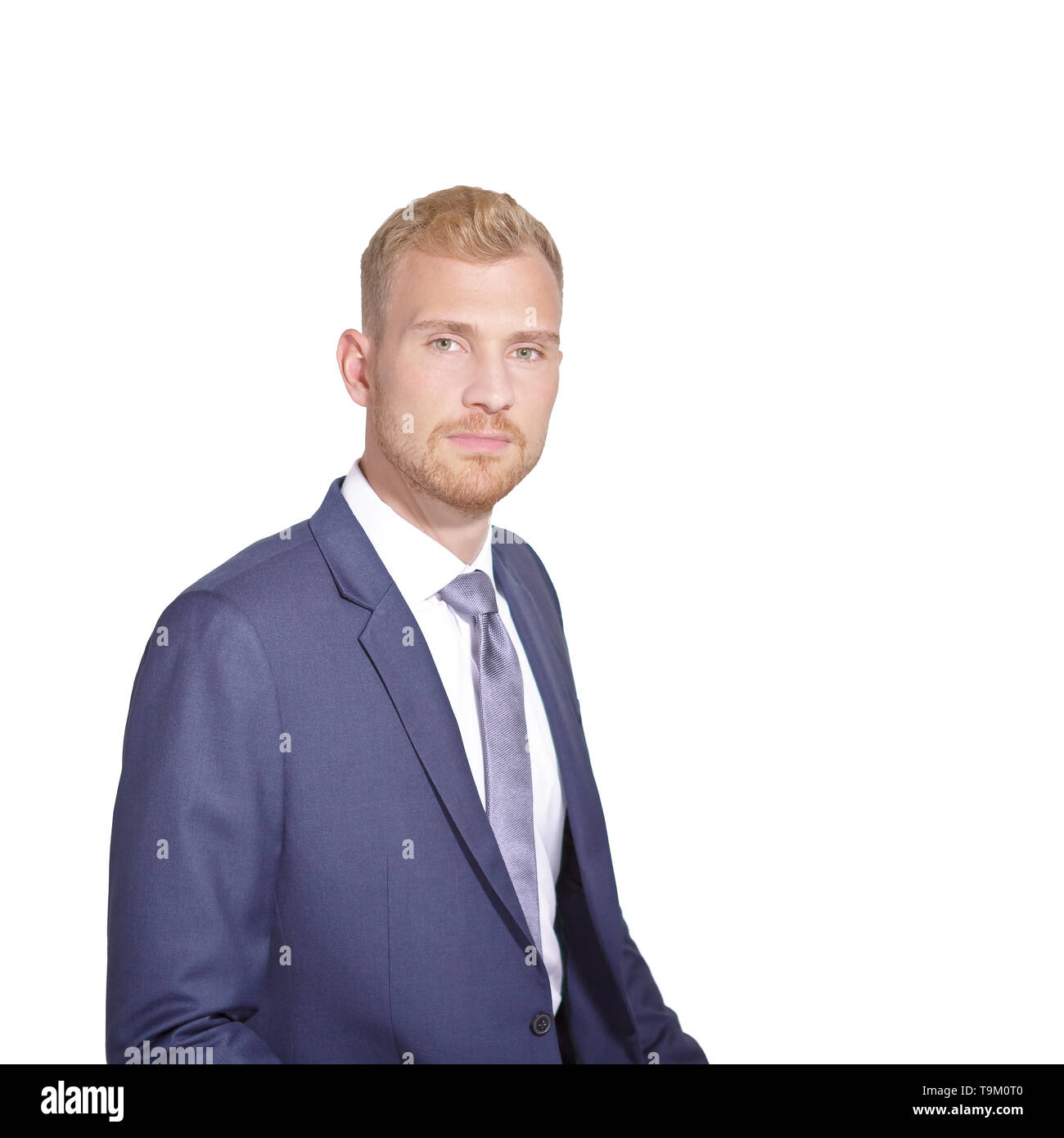 Businessman in his 20s in front of a white background, wearing a blue suit and tie, looking confident. Stock Photo