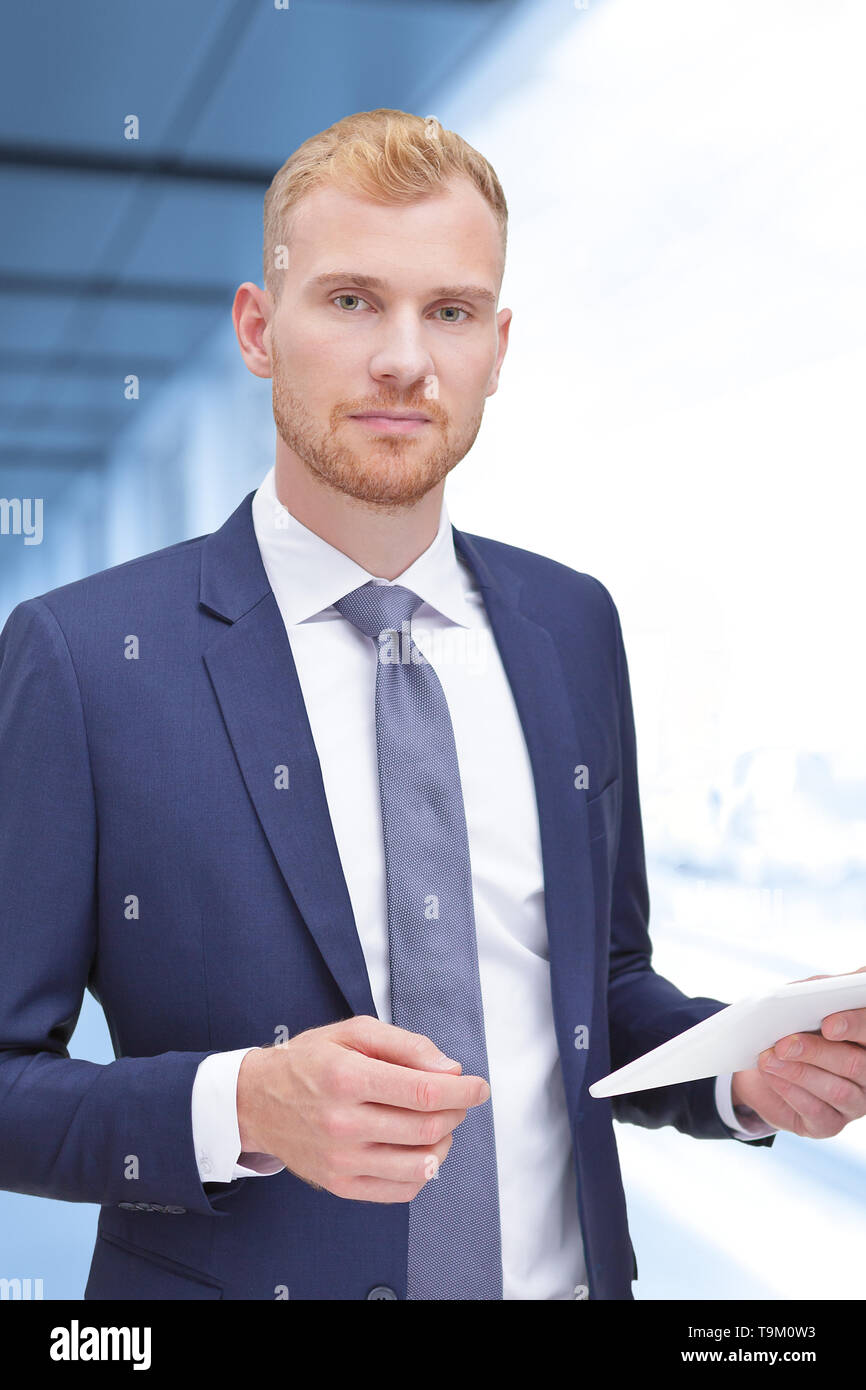 Male bank adviser, insurance consultant or real estate agent with white tablet computer inside an office building. Stock Photo