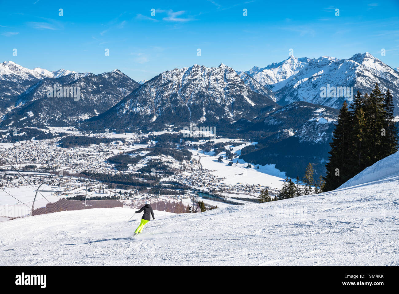 Panorama view of  snow covered Austrian Alps in winterabove the small town Reutte, with ski slope and skiing people in foreground, Tyrol, Austria Stock Photo