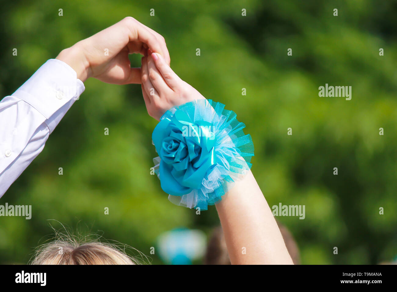 The hand of a man in a white shirt and a woman with a blue flower raised up on a green background. Festive, wedding, birthday concept, spring, summer Stock Photo