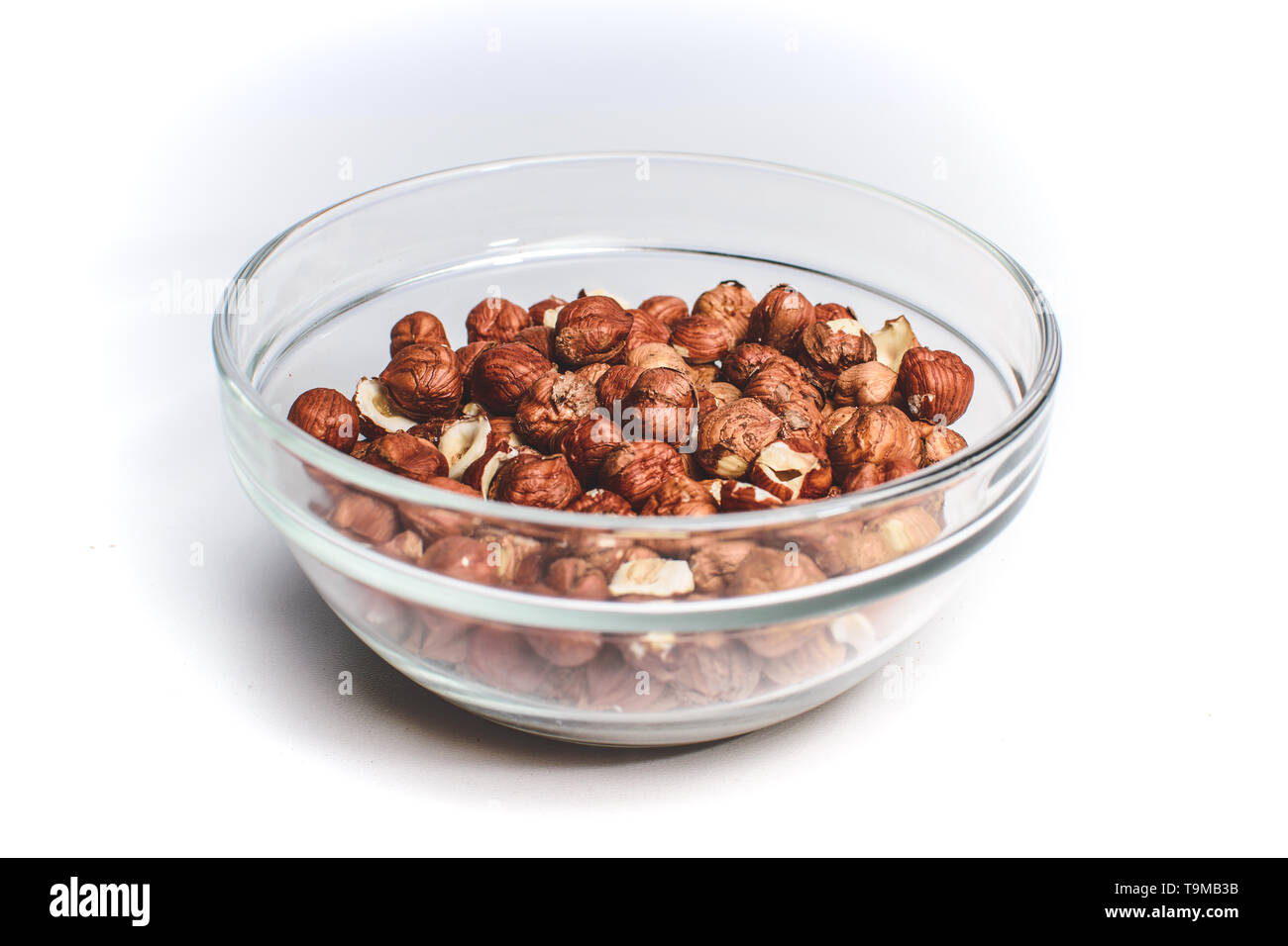 Isolated crystal bowl with hazelnuts against white background. Peeled nuts Stock Photo
