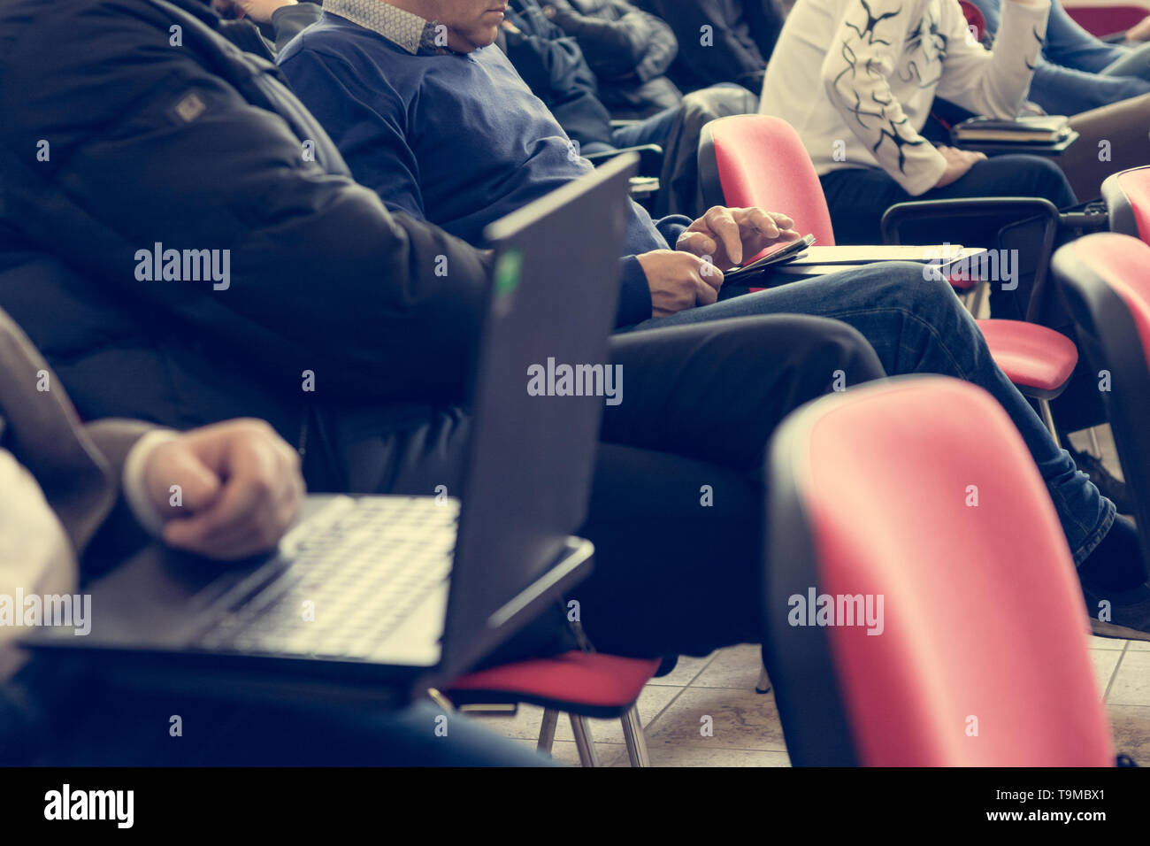 Student writing notes during conference training session Stock Photo