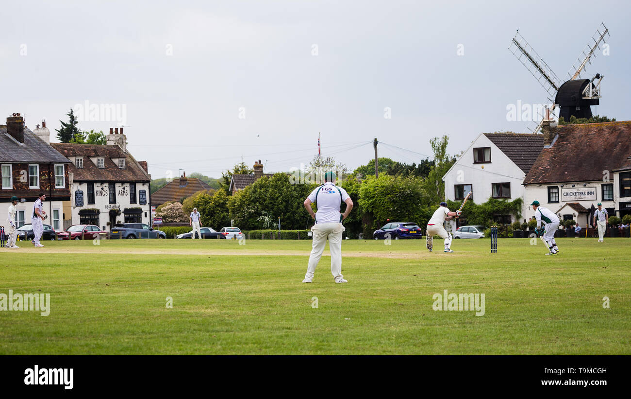 Cricket on the village green in Meopham, Kent. the Cricketers pub and Windmill can be seen in the background. Stock Photo