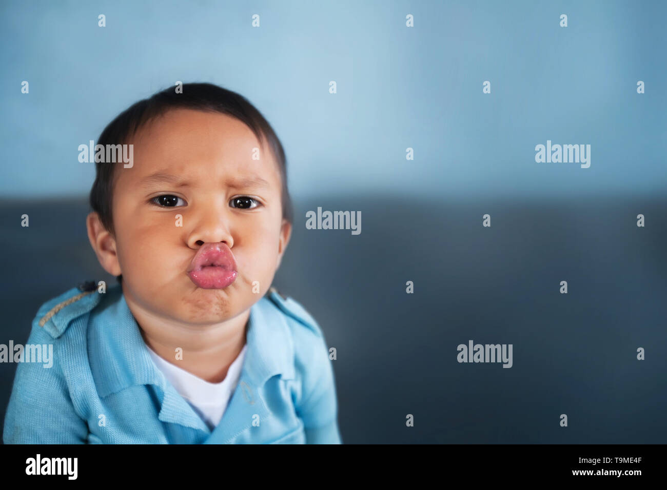 Young boy puckering up his lips to give a kiss and wearing a light blue vintage shirt. Stock Photo