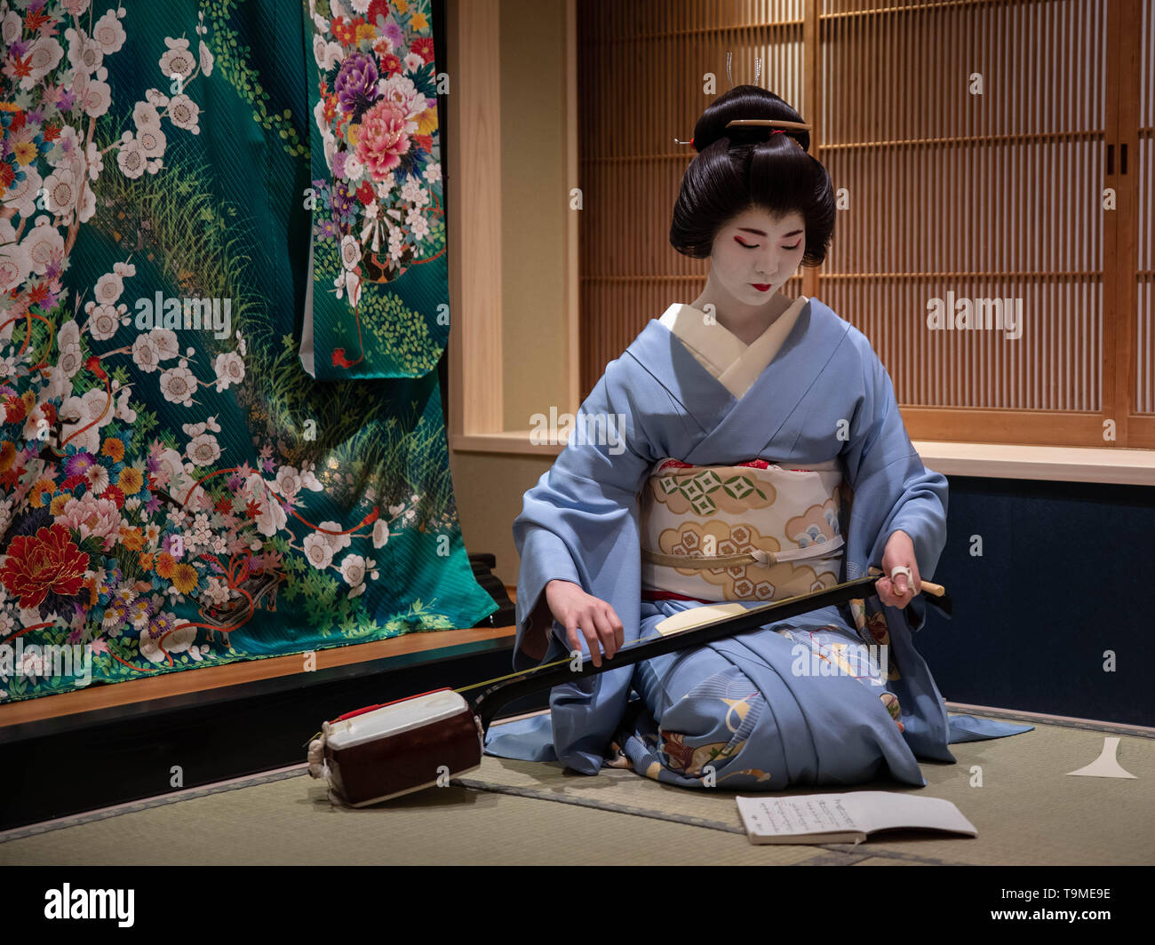 Kyoto, Japan - May 19, 2019: Young geisha in training, called a maiko, tunes her instrument prior to performance in traditional japanese inn Stock Photo