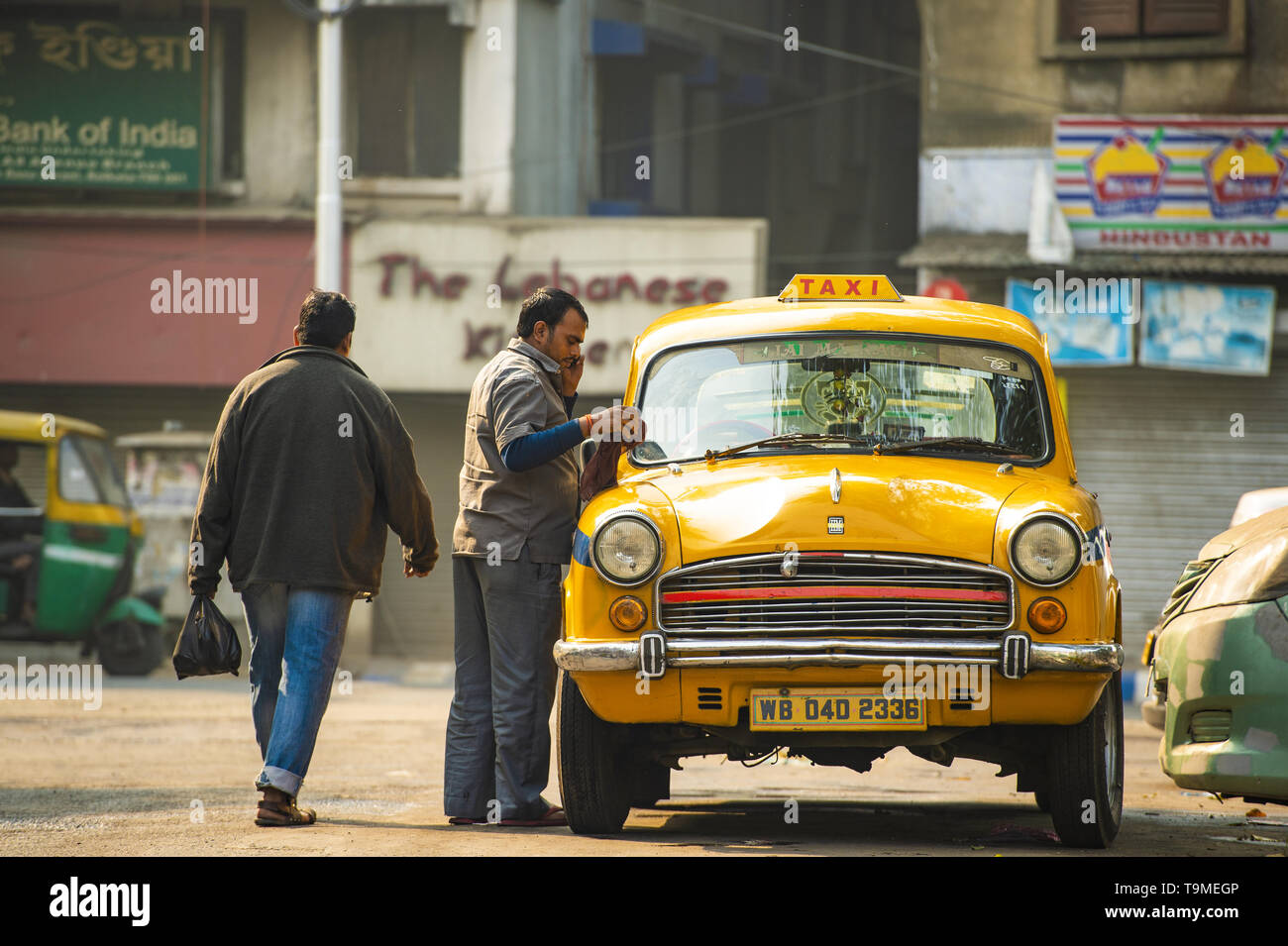 A taxi driver is washing an Ambassador taxi in Kolcata. The Ambassador taxi is no more built by Hindustan Motors Stock Photo