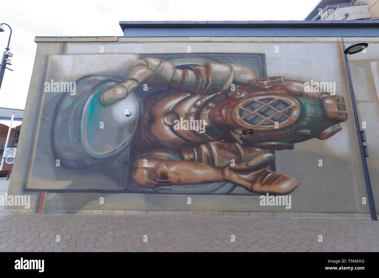 A painted mural of a deep sea diver climbing out of a washing machine on apartment blocks in Brewery Wharf,Leeds, West Yorkshire. Stock Photo